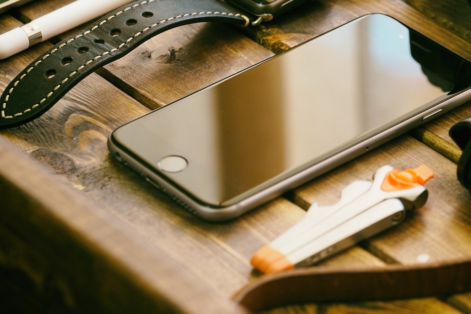 木のテーブルに置かれた、画面の消えたスマートフォン